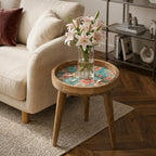 Teal & Pink Floral Glass-Top Mango Wood Side Table, shown beside a sofa in a styled room.