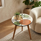 Japandi Botanical Print Round Side Table, shown beside a sofa in a styled room.